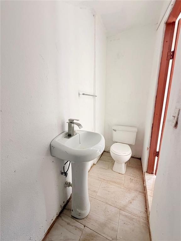 A small bathroom features a white pedestal sink, a toilet, and light-colored tile flooring — Calle 601 BLOQUE 224 COMERCIAL 1, CAROLINA, PR