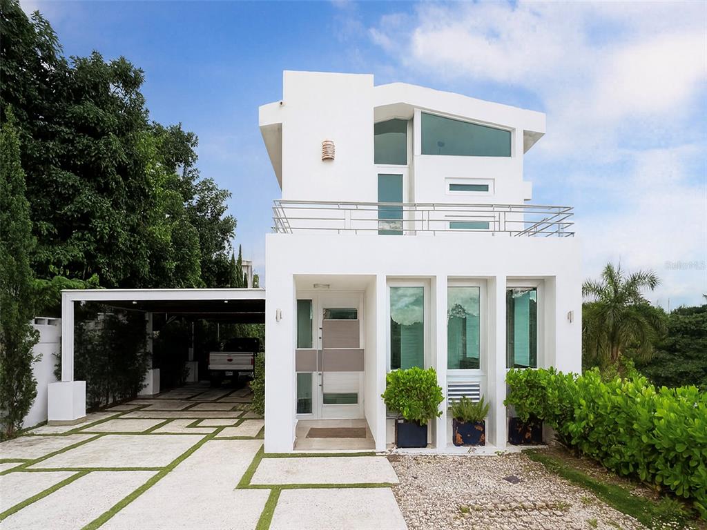 A modern two-story white house with a carport, balcony, and large glass windows — SR-830 Int LA FLORESTA SECTOR Lot 3, BAYAMON, PR