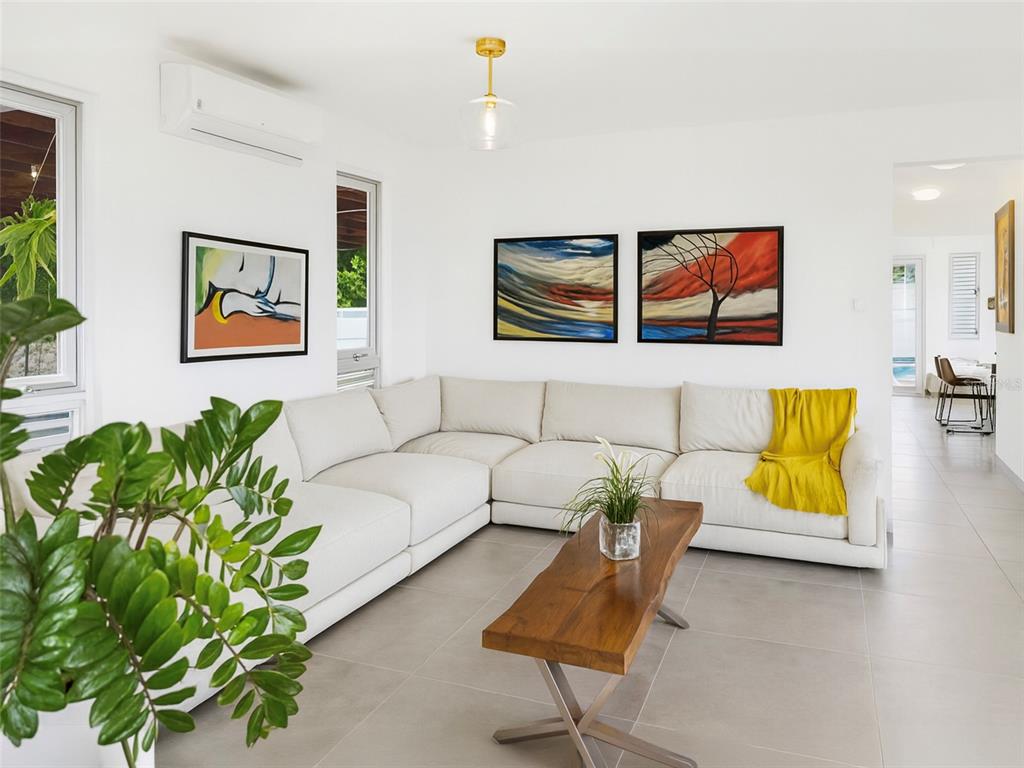 A living room features a white sectional sofa, a wooden coffee table, and abstract wall art — SR-830 Int LA FLORESTA SECTOR Lot 3, BAYAMON, PR
