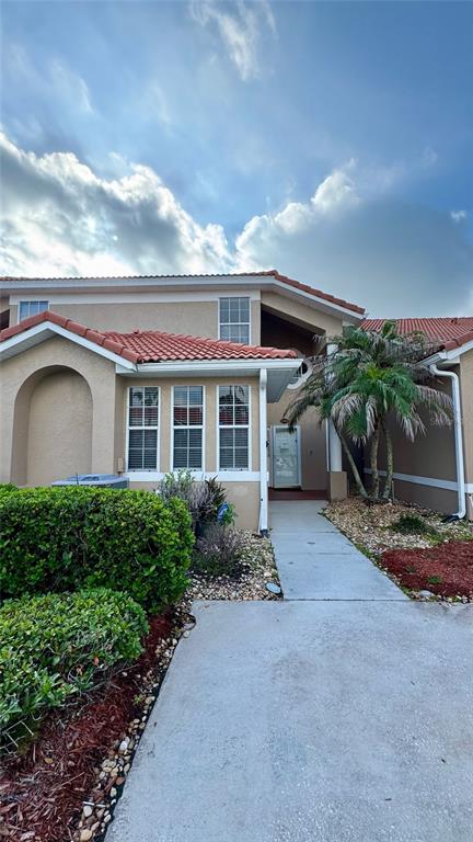 A two-story residential building features a tiled roof, beige stucco siding, and a concrete walkway — 1705 SAINT TROPEZ COURT, KISSIMMEE, FL