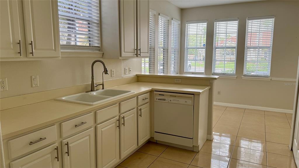 A kitchen features white cabinets, a double-basin sink, a dishwasher, and tile flooring — 1705 SAINT TROPEZ COURT, KISSIMMEE, FL