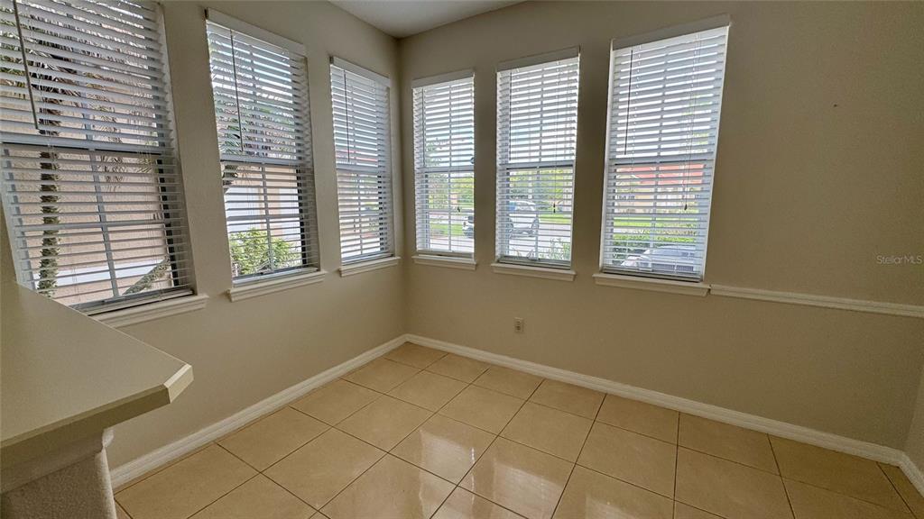 A sunroom with beige tile flooring, neutral walls, and multiple windows with white blinds — 1705 SAINT TROPEZ COURT, KISSIMMEE, FL