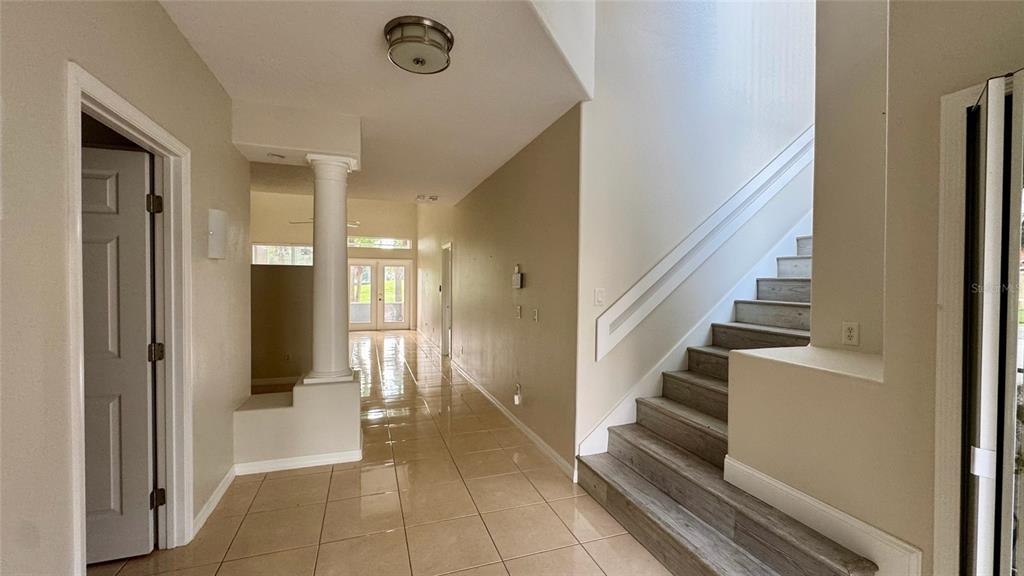 An interior view shows a tiled entryway with a staircase and a columned hallway — 1705 SAINT TROPEZ COURT, KISSIMMEE, FL