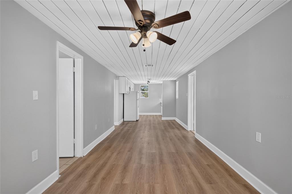 A long, narrow room features gray walls, wood-look flooring, and a white plank ceiling — 2947 GILLESPIE AVENUE, SARASOTA, FL