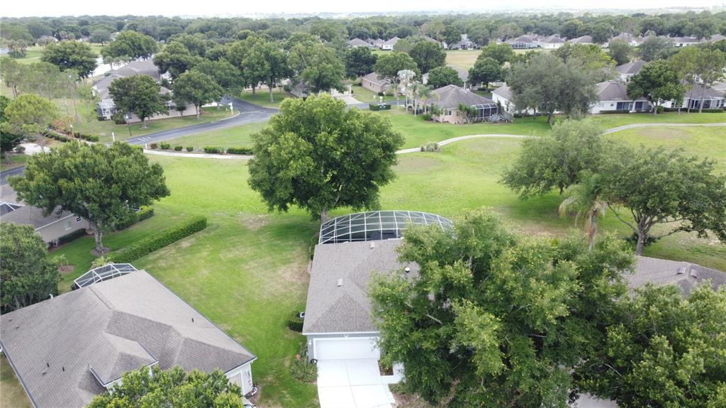 An aerial view shows a suburban house with a screened pool enclosure and surrounding trees — 2265 CALVERT COURT, CLERMONT, FL