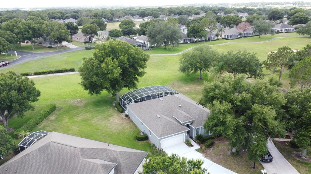 An aerial view shows a suburban house with a screened pool enclosure and large trees — 2265 CALVERT COURT, CLERMONT, FL