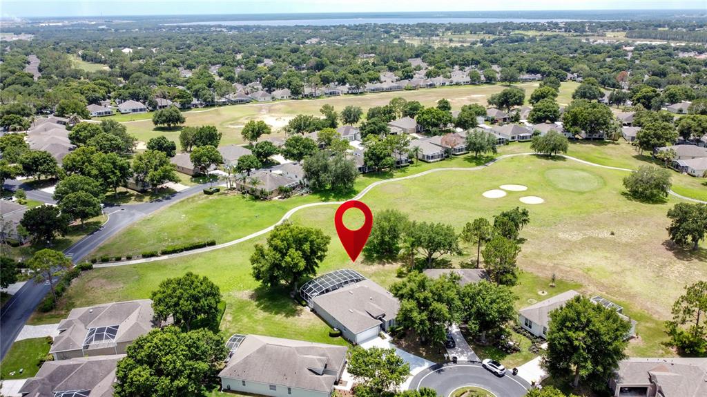 An aerial view shows a house with a screened pool enclosure bordering a golf course — 2265 CALVERT COURT, CLERMONT, FL