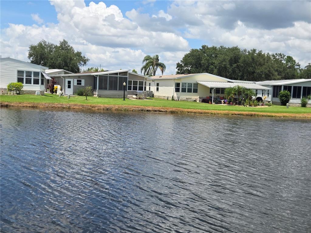 A row of manufactured homes sits along the edge of a calm lake — 88 STRAPHMORE DRIVE, HAINES CITY, FL
