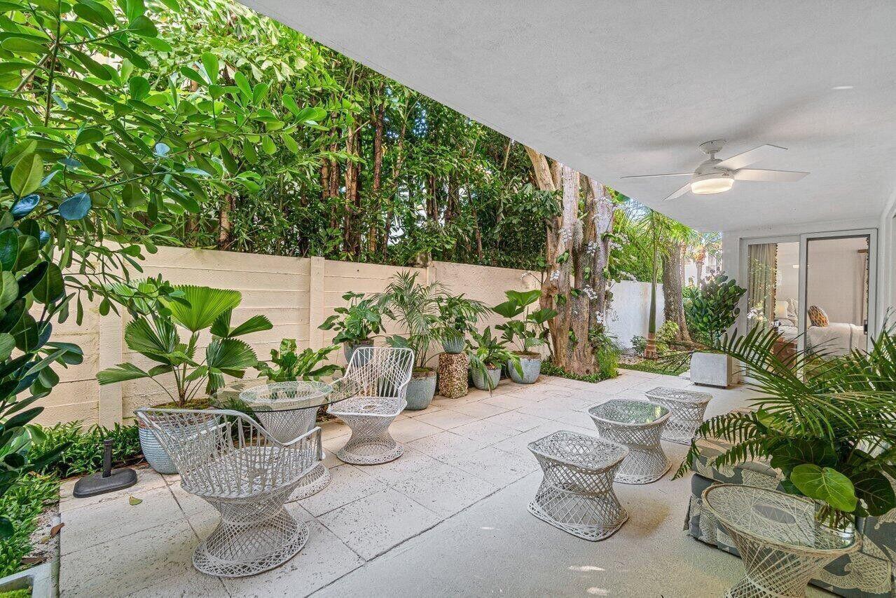 A covered patio features white wire furniture, potted plants, and a concrete wall — 226 Brazilian Avenue # 1a, Palm Beach FL 33480, PALM BEACH, FL