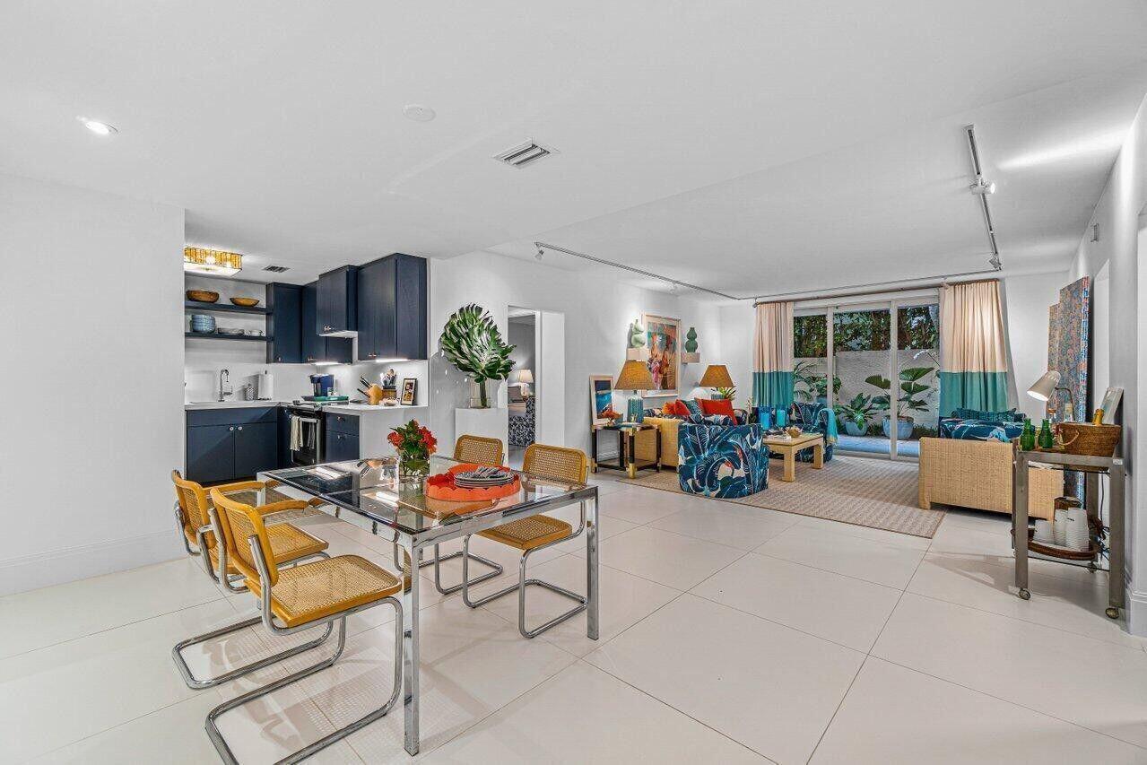 An open-concept living and dining area features white tile floors, dark cabinetry, and patio access — 226 Brazilian Avenue # 1a, Palm Beach FL 33480, PALM BEACH, FL