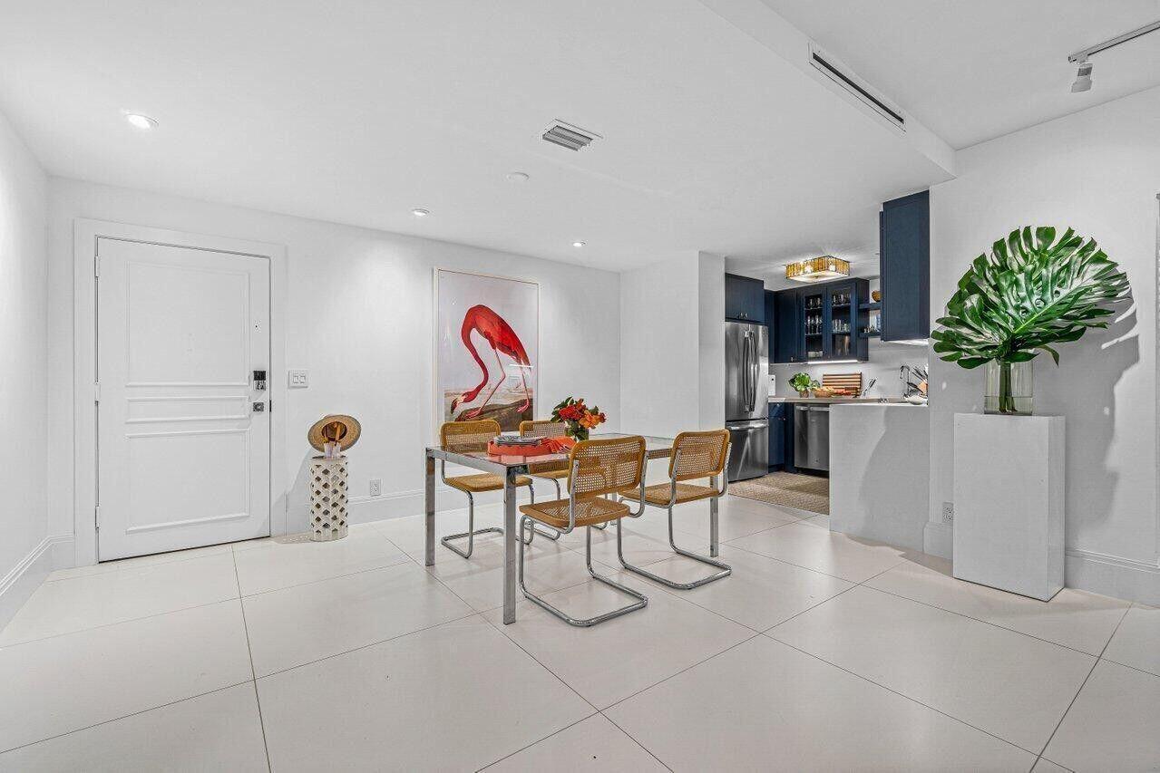 A dining area with a glass table and rattan chairs sits next to a kitchen — 226 Brazilian Avenue # 1a, Palm Beach FL 33480, PALM BEACH, FL