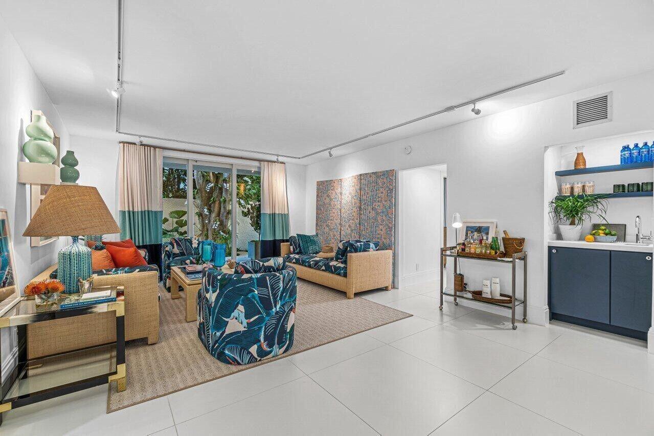 A bright living room features tropical-patterned furniture, a wet bar, and large sliding glass doors — 226 Brazilian Avenue # 1a, Palm Beach FL 33480, PALM BEACH, FL