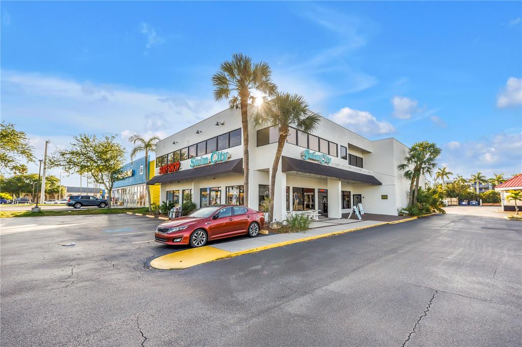 A two-story commercial building with a red sedan parked in front of the entrance — 1960 STICKNEY POINT ROAD UNIT 217, SARASOTA, FL
