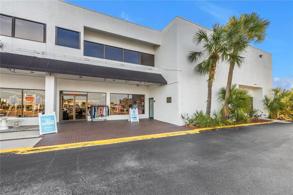 A two-story white commercial building features a black awning, glass storefront, and palm trees — 1960 STICKNEY POINT ROAD UNIT 217, SARASOTA, FL