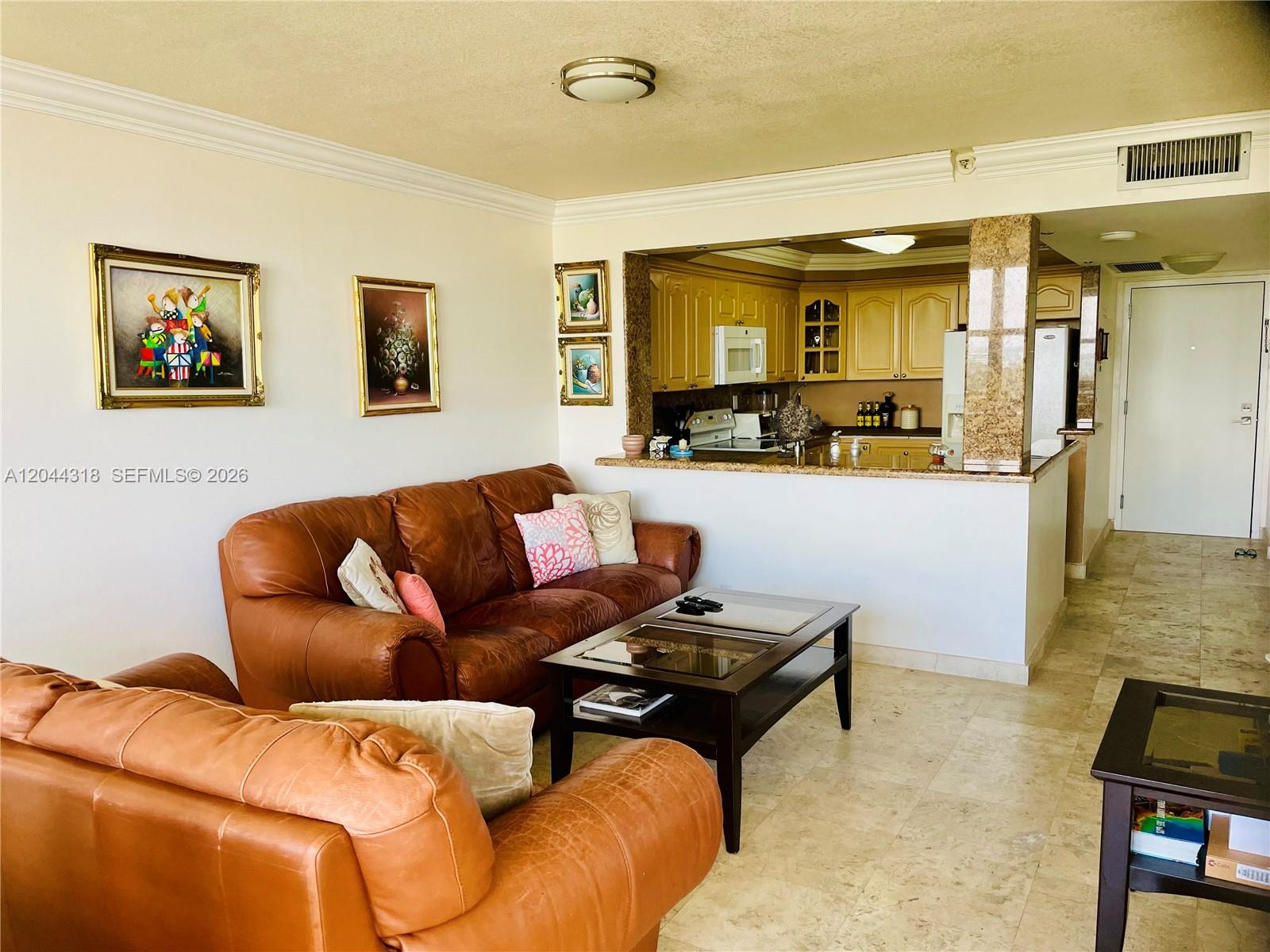 A living room with leather sofas and a coffee table opens to a kitchen area — 2555 Collins Ave # 2006, Miami Beach FL 33140, MIAMI BEACH, FL
