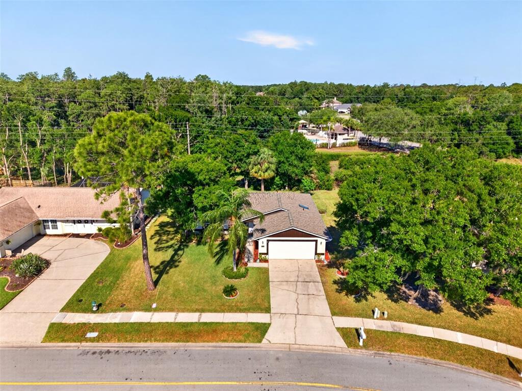 An aerial view shows a single-story house with a driveway and surrounding trees — 549 LONGWOOD CIRCLE, OLDSMAR, FL