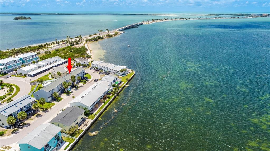 An aerial view shows a waterfront townhouse complex with a red arrow pointing to one unit — 2643 ST JOSEPHS DRIVE W, DUNEDIN, FL