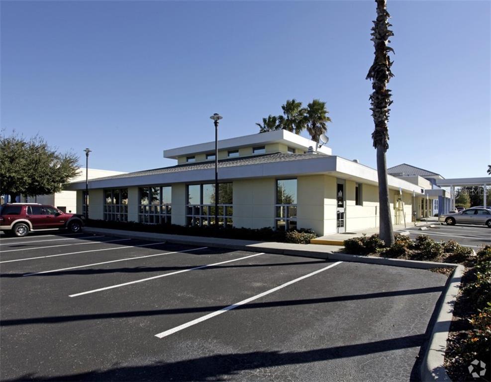 A single-story commercial building with a flat roof, large windows, and a paved parking lot — 7485 SANDLAKE COMMONS BOULEVARD, ORLANDO, FL