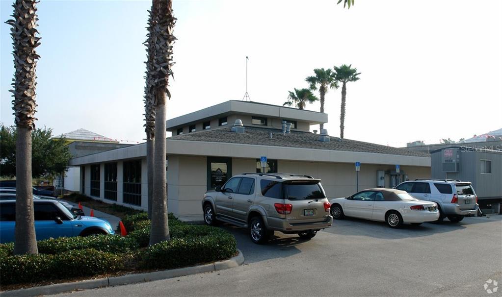 A single-story commercial building with a tan exterior and parking lot in front — 7485 SANDLAKE COMMONS BOULEVARD, ORLANDO, FL