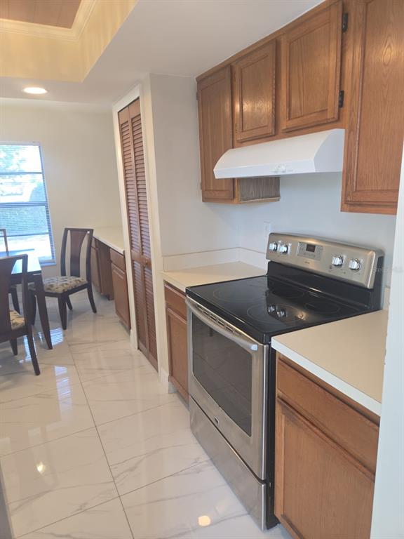 A kitchen with wood cabinets, a stainless steel stove, and white tile flooring — 1805 CORAL POINT DRIVE, CAPE CORAL, FL