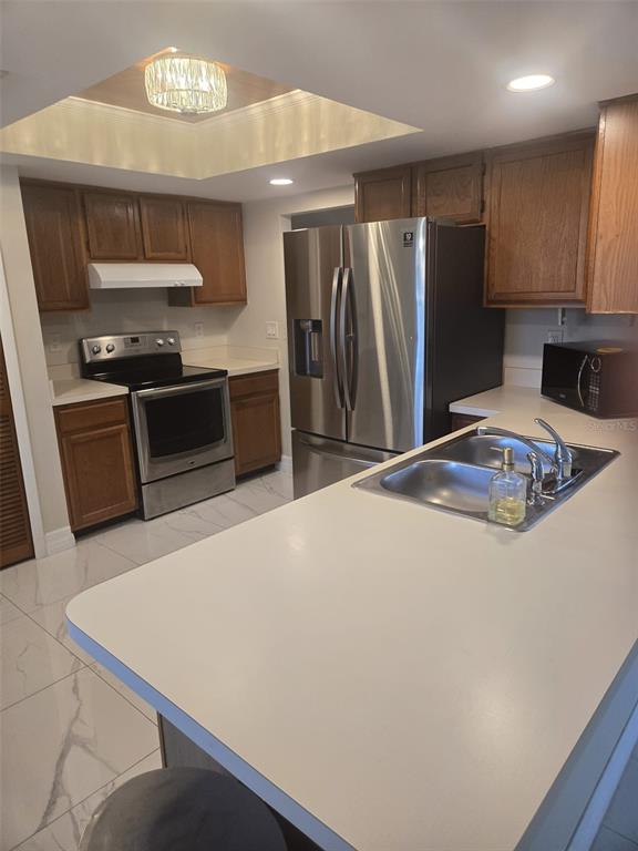 A kitchen features wood cabinets, stainless steel appliances, a white countertop, and white tile flooring — 1805 CORAL POINT DRIVE, CAPE CORAL, FL