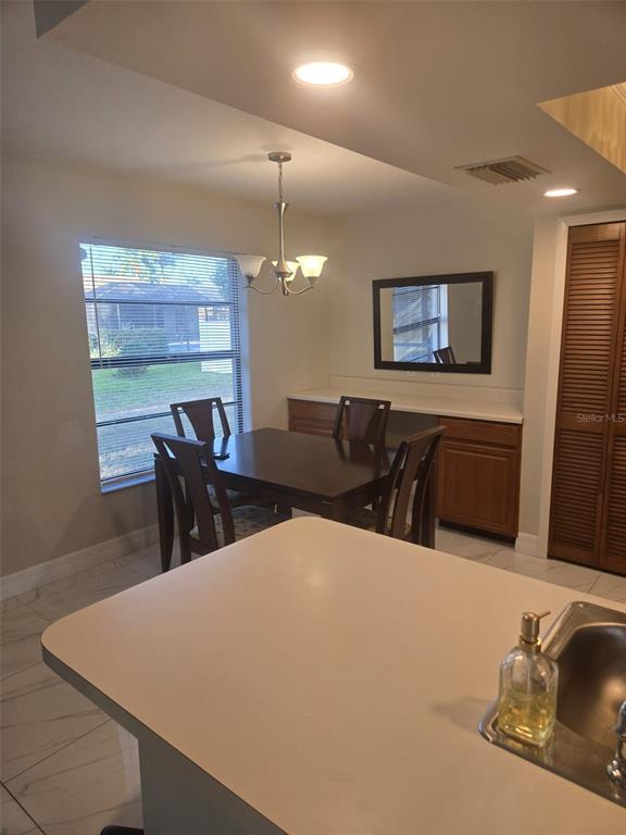 A dining area with a wooden table, chairs, and a built-in cabinet with a mirror — 1805 CORAL POINT DRIVE, CAPE CORAL, FL
