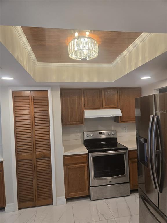A kitchen features wood cabinets, a stainless steel stove, and a recessed ceiling with lighting — 1805 CORAL POINT DRIVE, CAPE CORAL, FL