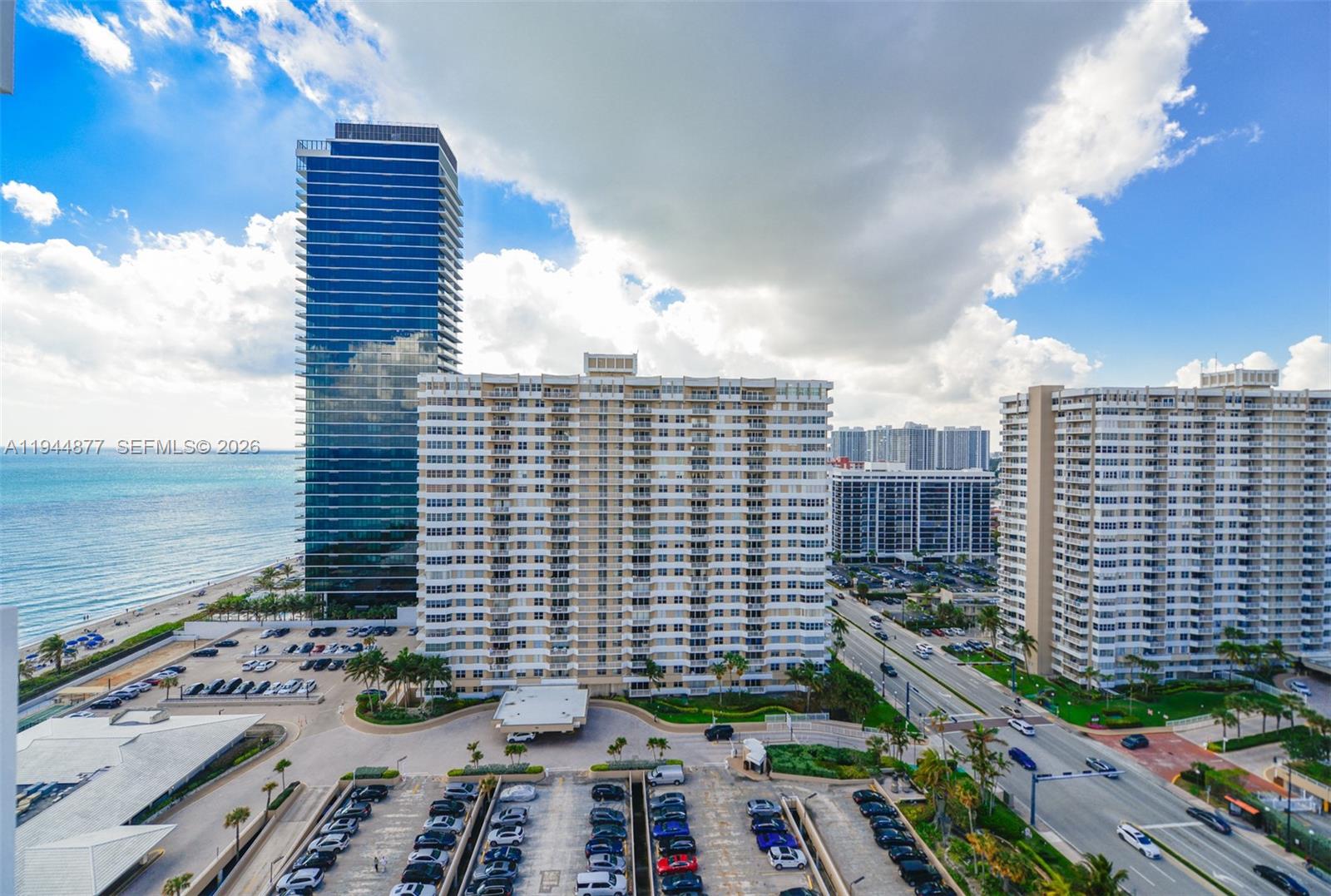 An aerial view shows several high-rise residential buildings near a beach and a parking lot — 1950 S Ocean Dr # 19E, Hallandale Beach FL 33009, HALLANDALE BEACH, FL