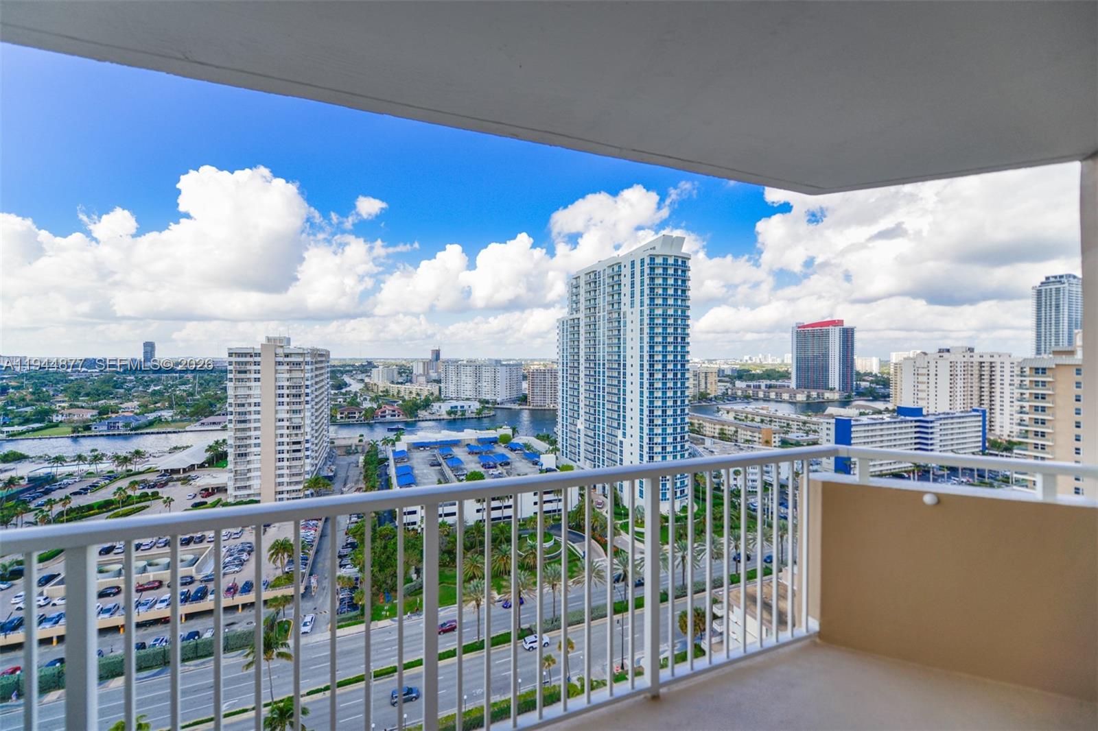 A high-angle view from a balcony overlooking a city skyline, waterway, and parking lot — 1950 S Ocean Dr # 19E, Hallandale Beach FL 33009, HALLANDALE BEACH, FL