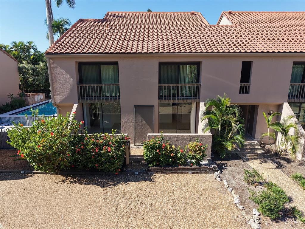 An exterior view of a two-story townhouse with a tiled roof, balconies, and landscaping — 117 PASS KEY ROAD UNIT 117, SARASOTA, FL