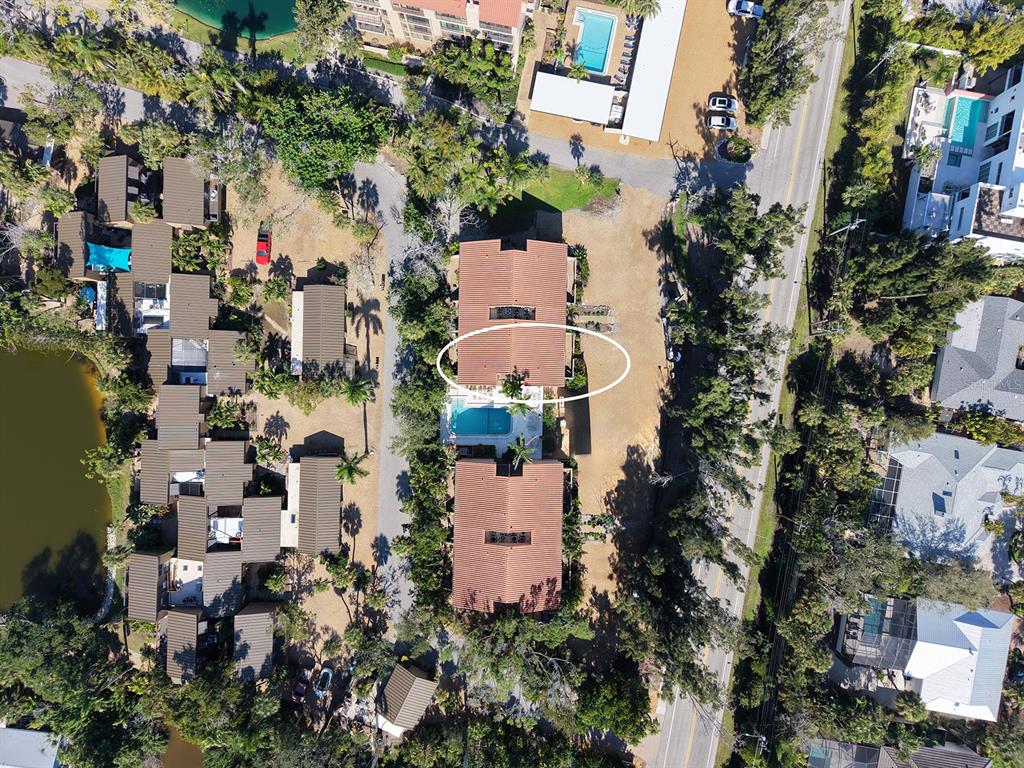 Aerial view of a residential complex with two buildings, a swimming pool, and surrounding trees — 117 PASS KEY ROAD UNIT 117, SARASOTA, FL