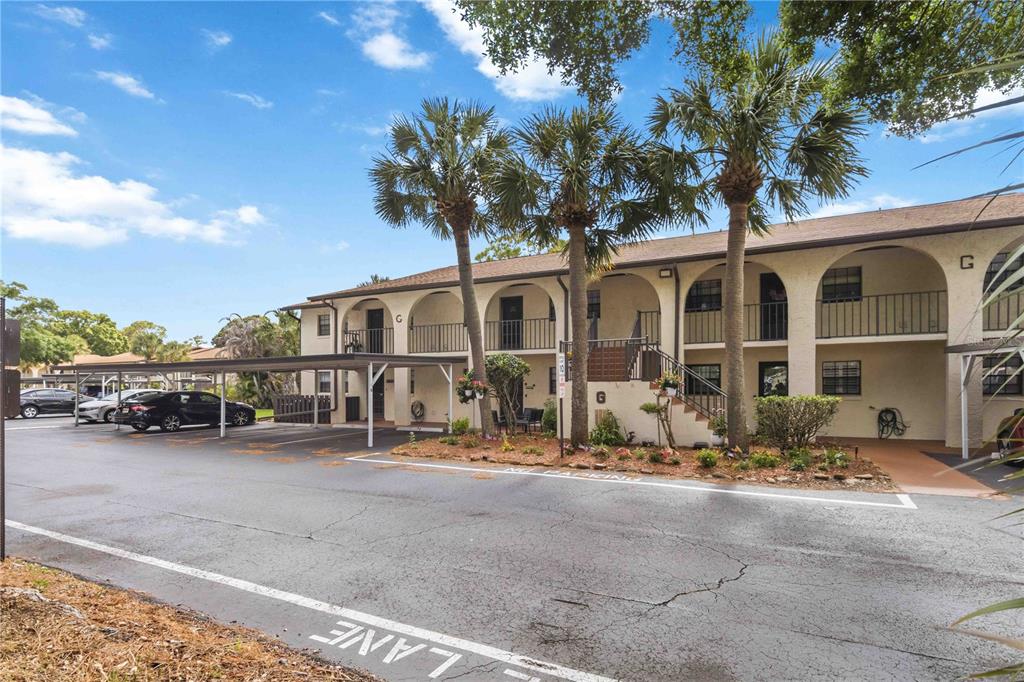 A two-story apartment building with arched walkways, palm trees, and a covered parking area — 1675 S FISKE BOULEVARD UNIT G227, ROCKLEDGE, FL
