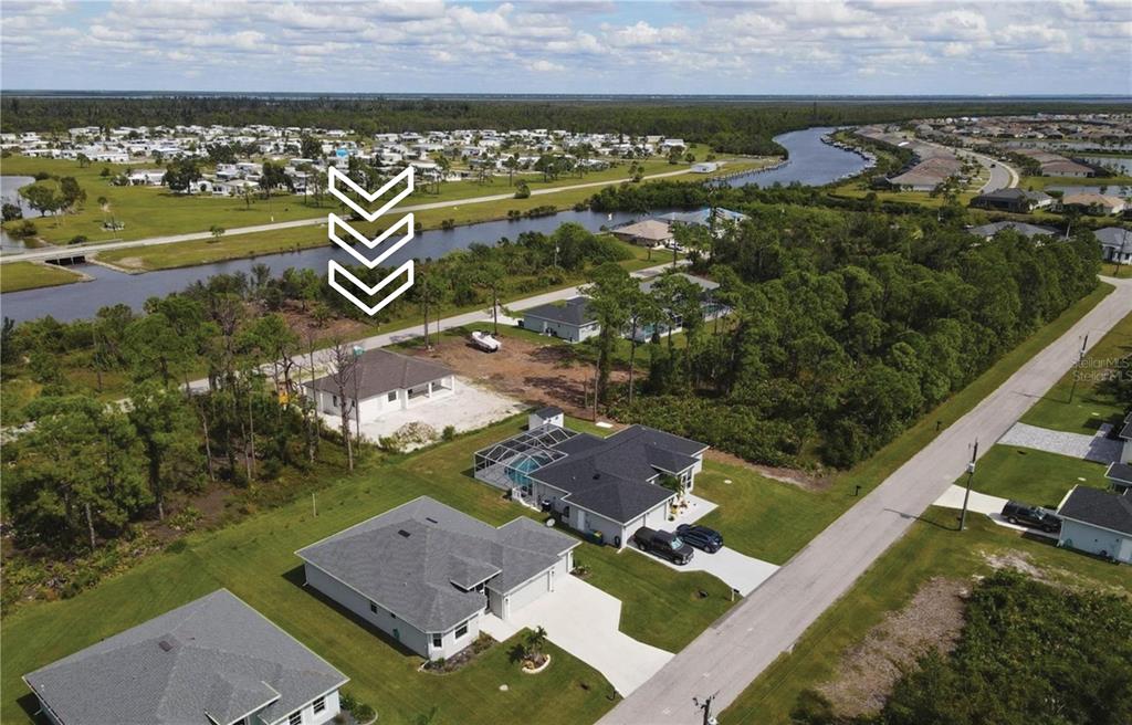 An aerial view shows a new house under construction near a canal and residential neighborhood — 14206 OSTROM AVENUE, PORT CHARLOTTE, FL