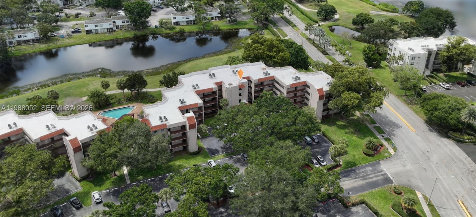 An aerial view shows a multi-story apartment building with a pool and surrounding parking lots — 1811 Sabal Palm Dr # 408, Davie FL 33324, DAVIE, FL