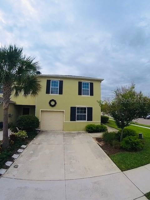 A two-story, light green house features a single-car garage and a concrete driveway — 403 ARBOR LAKES DRIVE, DAVENPORT, FL