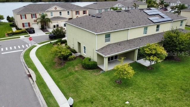 An aerial view shows townhouses with solar panels and a nearby lake — 403 ARBOR LAKES DRIVE, DAVENPORT, FL