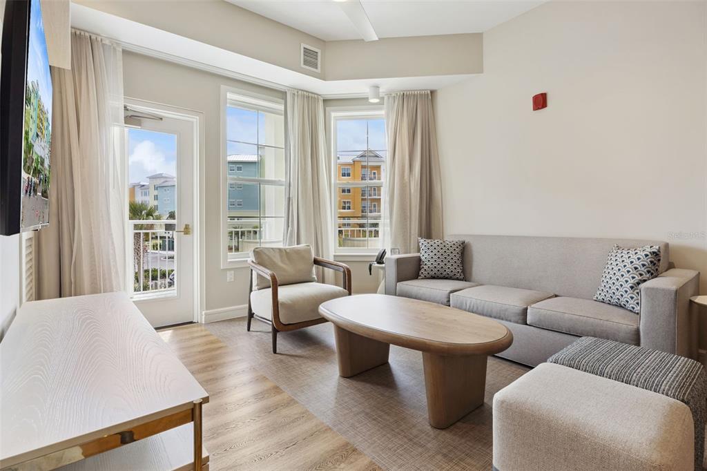A living room features a gray sofa, a wooden coffee table, and a balcony door — 3151 SUNSET WALK DRIVE UNIT 1214, KISSIMMEE, FL