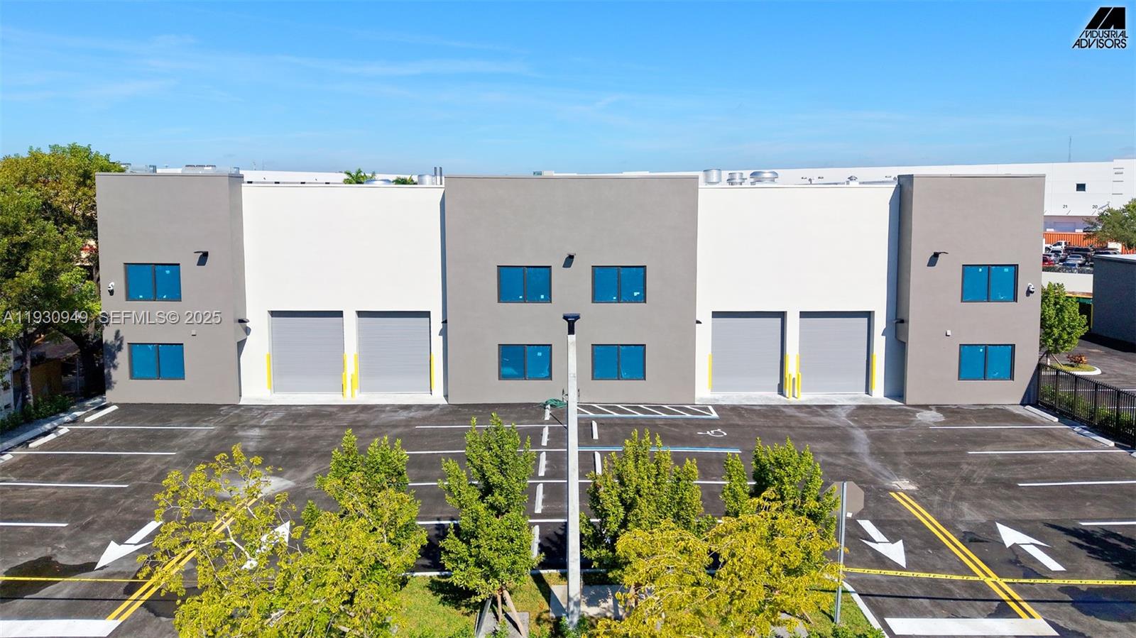 An exterior view of a modern industrial building with gray and white walls and parking — 10941 NW 123rd St, Medley FL 33178, MEDLEY, FL