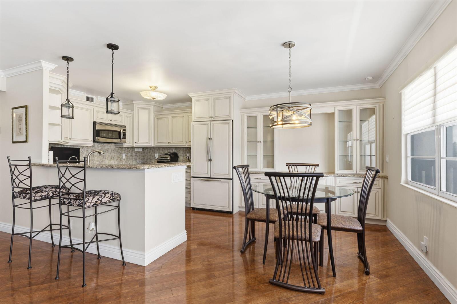 A kitchen with white cabinets, granite countertops, a breakfast bar, and a dining area — 4037 Ainslie C, Boca Raton FL 33434, BOCA RATON, FL