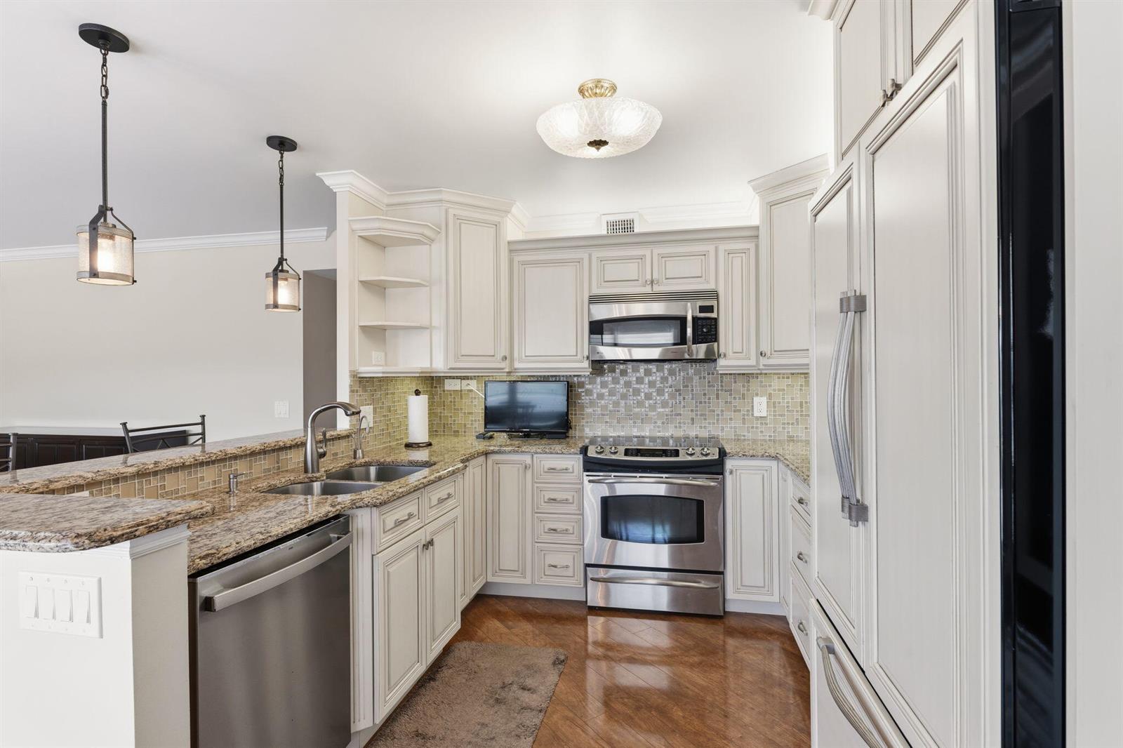 A kitchen with cream cabinets, stainless steel appliances, granite countertops, and a tile backsplash — 4037 Ainslie C, Boca Raton FL 33434, BOCA RATON, FL