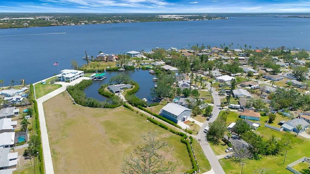 An aerial view shows a waterfront neighborhood with houses, a central pond, and green lawns — 217 22ND STREET COURT NE, BRADENTON, FL