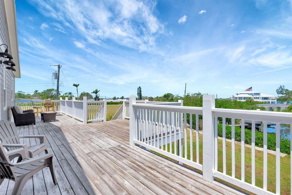 A wooden deck with white railings overlooks a grassy yard and a nearby waterway — 217 22ND STREET COURT NE, BRADENTON, FL
