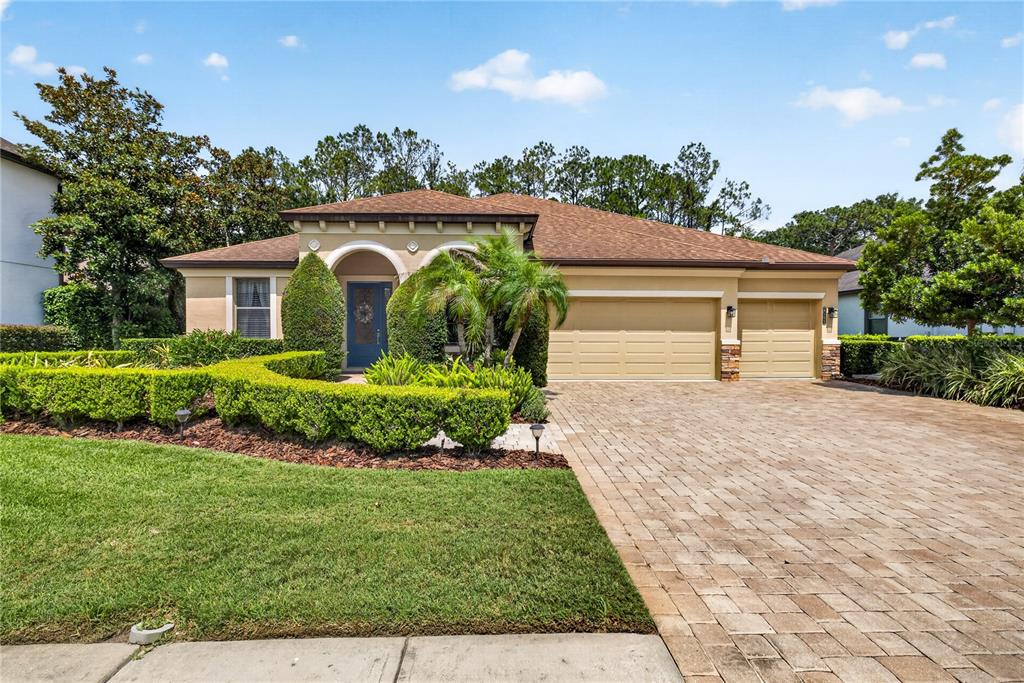 A single-story house with a tan stucco exterior, a three-car garage, and a paved driveway — 4726 LAGO VISTA CIRCLE, LAND O LAKES, FL