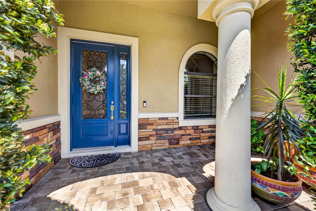 A blue front door with a wreath stands next to a stone-accented wall and column — 4726 LAGO VISTA CIRCLE, LAND O LAKES, FL