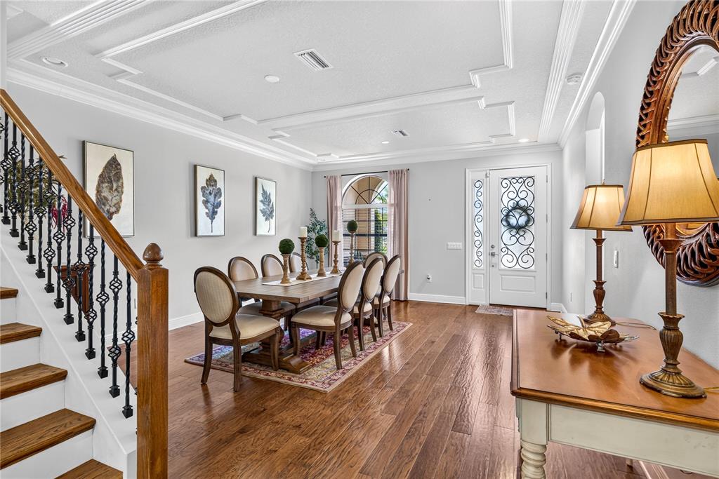 A dining room features a wooden table, chairs, hardwood floors, and a staircase with railing — 4726 LAGO VISTA CIRCLE, LAND O LAKES, FL