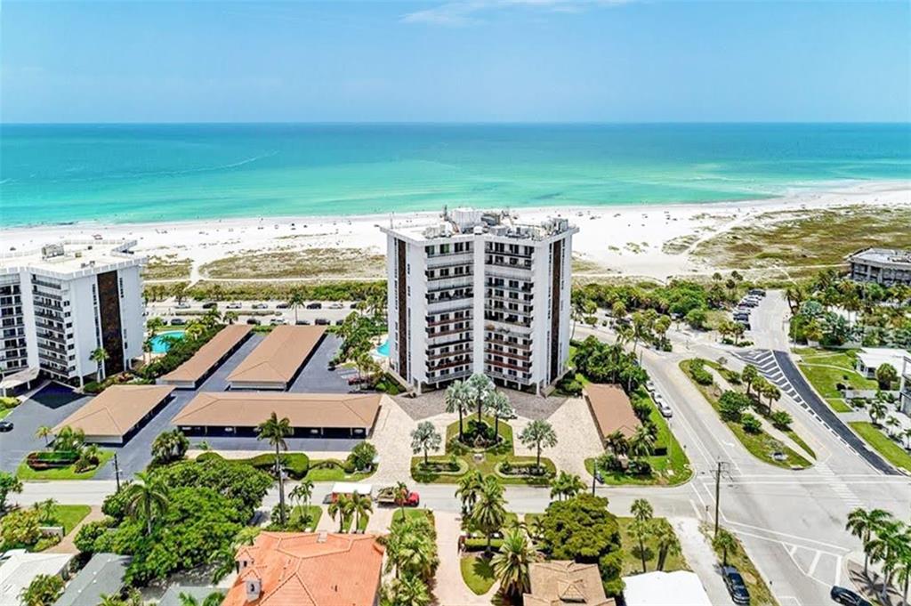 An aerial view shows a high-rise condominium building near a beach and coastal road — 1 BENJAMIN FRANKLIN DRIVE UNIT 3, SARASOTA, FL