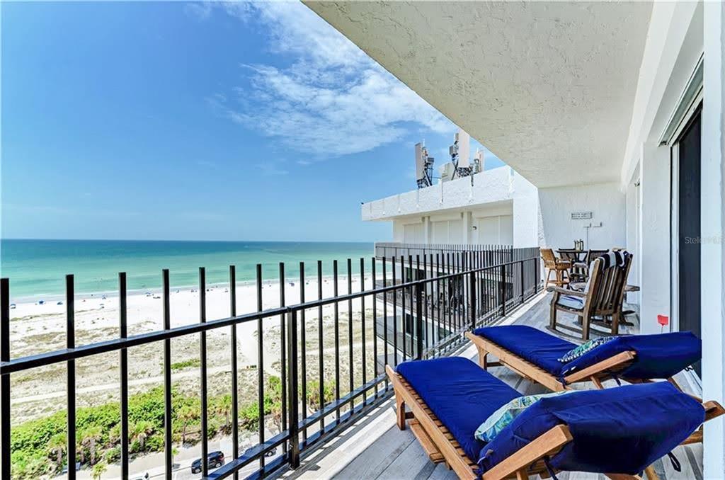 A balcony with lounge chairs overlooks a sandy beach and the ocean — 1 BENJAMIN FRANKLIN DRIVE UNIT 3, SARASOTA, FL
