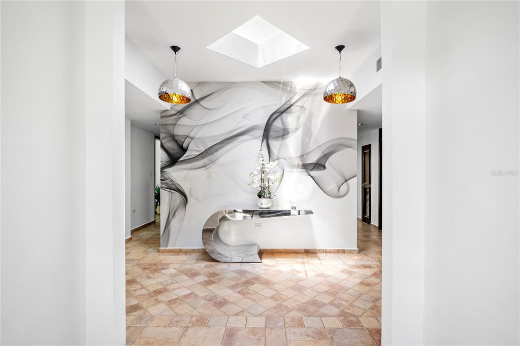 A modern entryway features a smoke-patterned accent wall, a curved metallic console table, and skylight — 35 PASEO LAS PALMAS, DORADO, PR