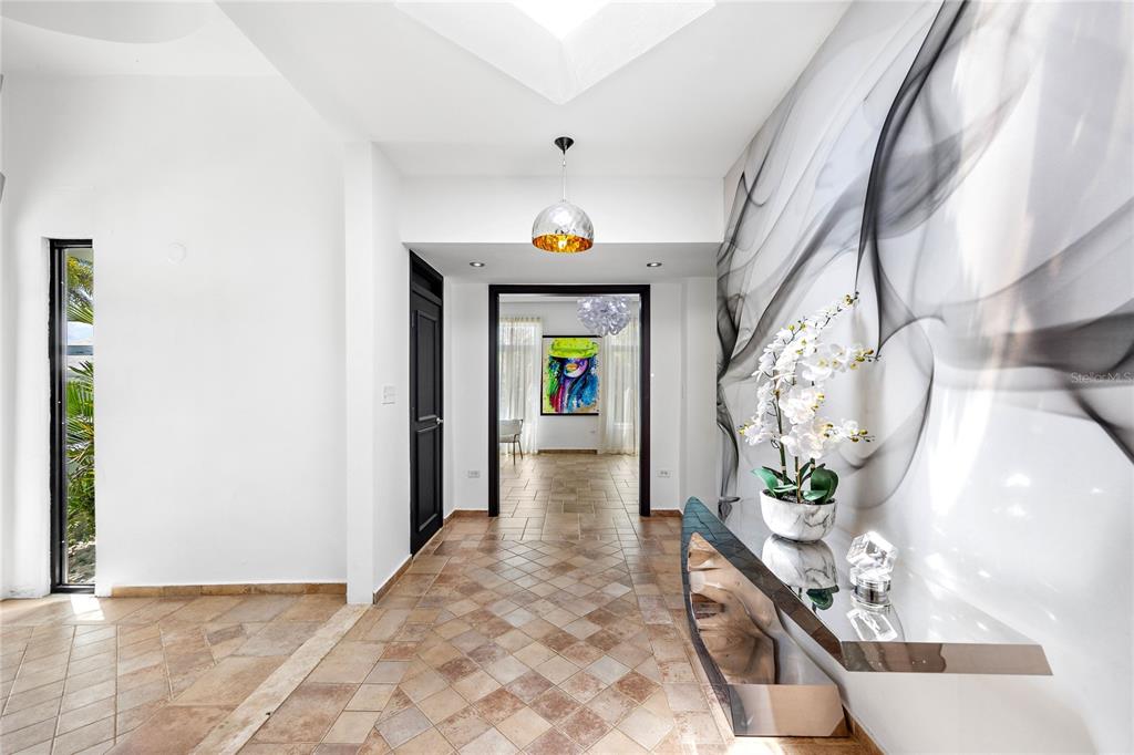 A tiled entryway features a metallic console table, a large abstract wall mural, and orchids — 35 PASEO LAS PALMAS, DORADO, PR