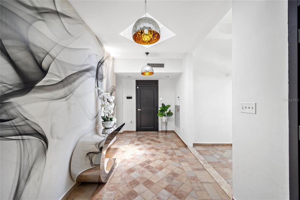 A modern entryway features a smoke-patterned wall mural, tile flooring, and two hanging pendant lights — 35 PASEO LAS PALMAS, DORADO, PR